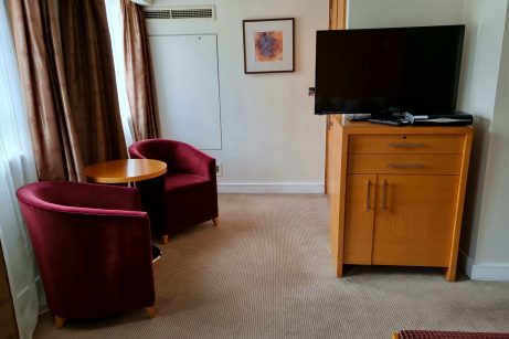 TV lounge in hotel room, London. Comfortable seating area with a television and cozy ambiance.