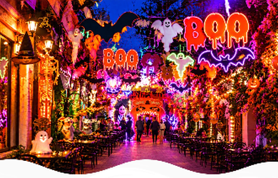 London street decorated for Halloween with neon BOO signs, ghosts and pumpkin lights